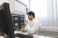 Ein Arzt sitzt vor drei Bildschirmen mit Röntgenaufnahmen und dirktiert in ein Diktiergerät.
