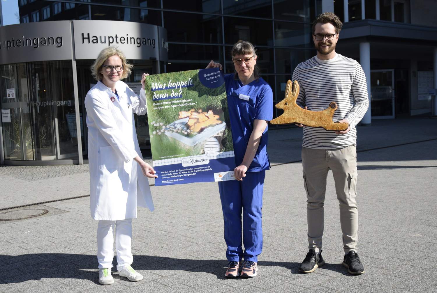 3 Personen präsentieren Plakat und großes Gebäck