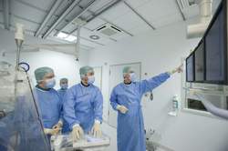 Vier Ärzte in blauer OP-Kleidung blicken auf einen Bildschirm
